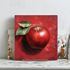 a painting of an apple with green leaves on it sitting on top of a shelf