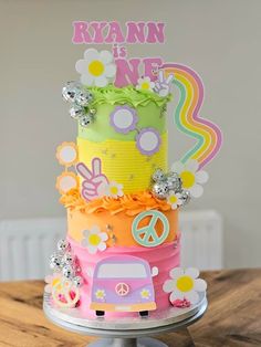 a multi layer cake decorated with flowers and peace signs