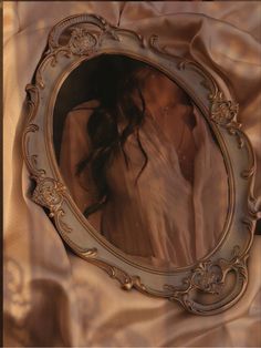 a woman's reflection in a mirror on a silk cloth covered bed sheet,