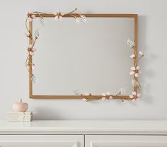 a white dresser with a mirror and flowers on it