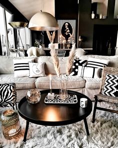 a black and white living room with zebra print pillows on the couch, coffee table