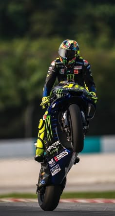 a man riding a motorcycle on top of a race track with trees in the background