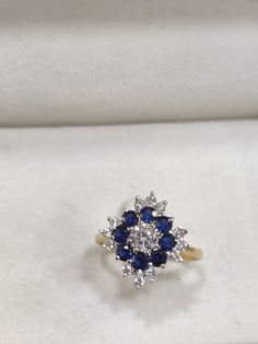 a diamond and blue sapphire ring sits in a white box on top of a table