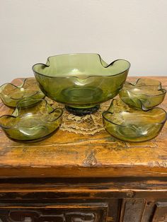 a green glass bowl sitting on top of a wooden table next to other bowls and dishes