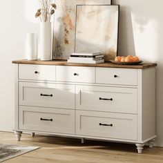 a white dresser with drawers and pictures on top