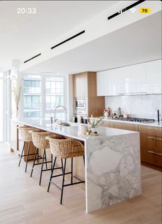 a large kitchen with marble counter tops and bar stools next to an open floor plan