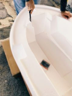 a person is painting the inside of a boat with paintbrushes and paper on it