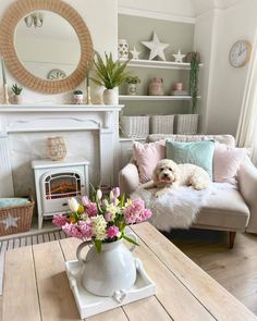 a living room filled with furniture and a dog laying on top of a couch next to a fire place