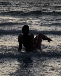 a woman laying in the ocean at sunset