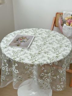 a white table with flowers on it and a book sitting on top of the table