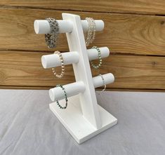 a white jewelry stand with beads and bracelets hanging from it's sides on a table