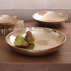 two pears are sitting in a bowl on a table with other bowls behind it