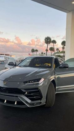 the front end of a silver lamb car parked in a parking lot with other cars