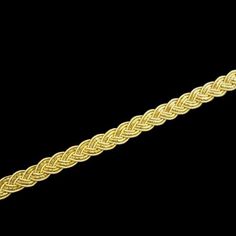 a gold braided bracelet on a black background with clippings to the side