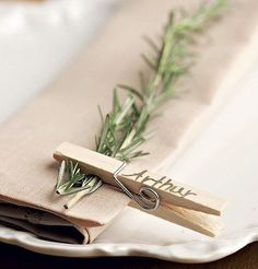 a pair of scissors sitting on top of a piece of cloth next to rosemary sprigs