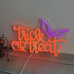 there is a neon sign that says trick or treat on the table next to it