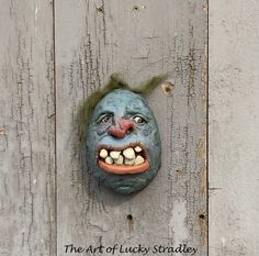 a creepy clown mask hanging on the side of a wooden wall with words written below it