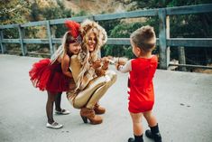 a woman dressed as a lion dancing with two children