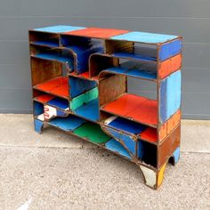 a multicolored wooden shelf sitting on top of a sidewalk next to a garage door