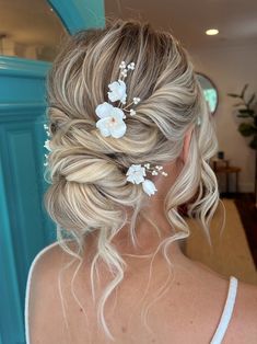 a woman with blonde hair and white flowers in her hair is looking at the mirror