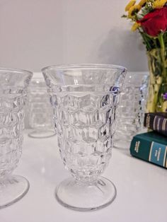 three clear glass vases sitting on top of a table next to books and flowers