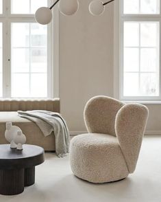 a living room filled with furniture next to two large windows and a round coffee table