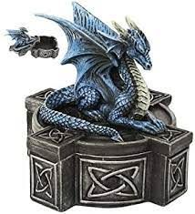 a blue dragon figurine sitting on top of a box with a key in it's mouth