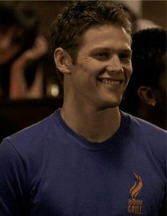 a young man smiling and wearing a blue shirt