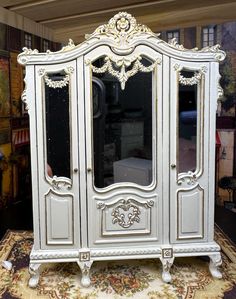 an ornate white armoire with mirrors on it