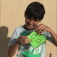 a young boy holding up a piece of green paper with the letter b on it