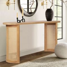 a console table with two candles on it in front of a mirror and wall hangings