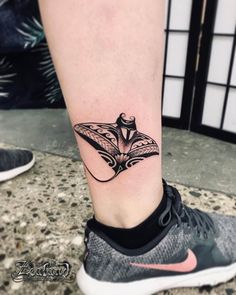 a black and white photo of a woman's foot with a butterfly tattoo on it