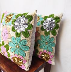 two decorative pillows sitting on top of a wooden table