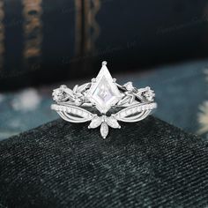 an engagement ring with a princess cut diamond in the center and leaves on each side