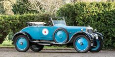 an old blue car is parked in front of some bushes