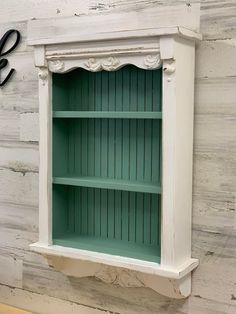 an old white book shelf with green paint