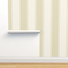 a white shelf sitting on the side of a wall next to a wooden floor in front of a striped wallpaper