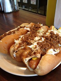 two hot dogs with toppings on a white plate