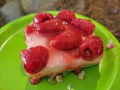 a green plate topped with a piece of cake covered in raspberry toppings