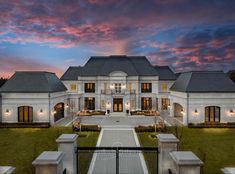 a large white house sitting on top of a lush green field under a cloudy sky