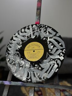 a black and white record sitting on top of a metal stand