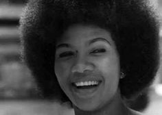 a woman with an afro smiling and looking at the camera