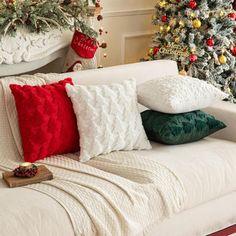 a living room decorated for christmas with white couches and red and green throw pillows