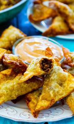 some fried food is on a plate with dipping sauce in the background and text overlay that reads taco wontons