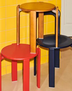 two chairs and a table in front of a yellow tiled wall with red, black, and blue accents