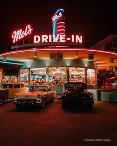 two cars parked in front of a drive - in restaurant at night with neon lights