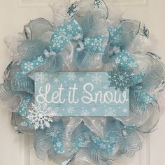 a wreath that says let it snow on the front door with blue and white decorations