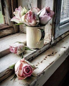 three pink roses are sitting in a white vase on a window sill next to an open window