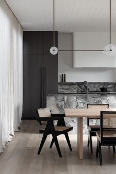 a dining room table and chairs in front of a kitchen counter with an oven on the wall