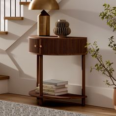 a wooden table with a lamp and books on it in front of a stair case